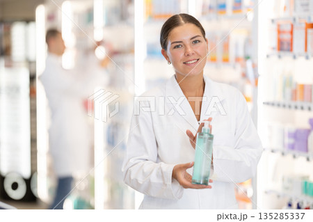 Girl pharmacist holds out bottle cosmetic 135285337