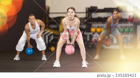 Sporty athletic woman in sportswear training with kettlebell in sport gym Sporty athletic woman in sportswear training with kettlebell in sport gym 135285421
