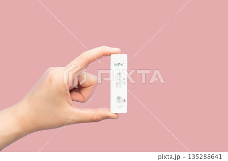 Hand holding HPV test kit for cervical cancer screening on pink background. Screening tool for at home use, that checks for high risk Human Papillomavirus types that can cause cervical cancer. 135288641