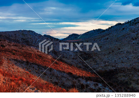 Dramatic Mountain Valley At Dusk With Blue Sky And Red Sunlit Hills 135288940