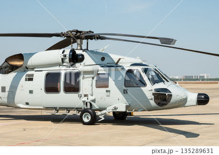 Gray painted modern military transport helicopter stationary on the ground 135289631