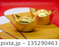 Paired golden sycee displayed on bright red background representing prosperity and festive celebration. 135290463