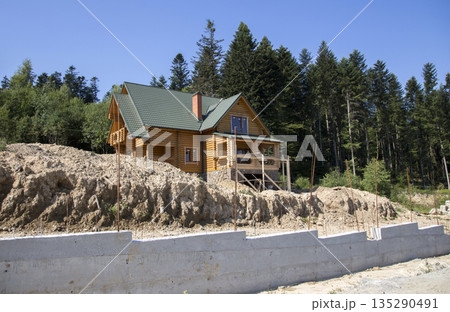 Construction of a wooden cottage in the forest area Construction of a wooden cottage in the forest area 135290491