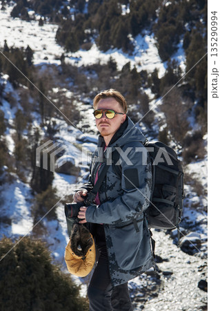 Young man hiker with backpack and camera on a winter mountain adventure Young man hiker with backpack and camera on a winter mountain adventure 135290994