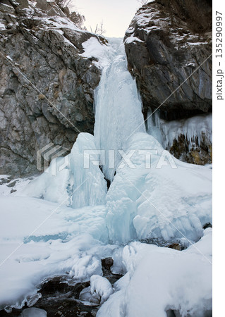 Frozen waterfall in winter mountain landscape. Ice formation on rock cliff 135290997