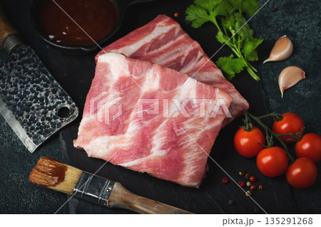 Raw meat. Raw pork ribs from the back with meat on a black background. background image 135291268
