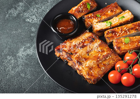 Hot grilled spare ribs from a summer BBQ served on a plate with sauce. Top view. Copy space Hot grilled spare ribs from a summer BBQ served on a plate with sauce. Top view. Copy space 135291278