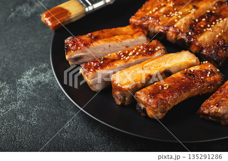 Hot grilled spare ribs from a summer BBQ served on a plate with sauce. Top view. Copy space Hot grilled spare ribs from a summer BBQ served on a plate with sauce. Top view. Copy space 135291286