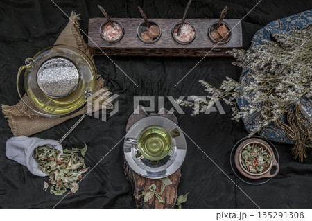 A Beautiful composition with a hot pandan leaf tea with indian marsh fleabane plant leaves and Safflower dried (Saffron substitute) at dark background. 135291308