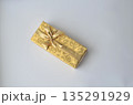 Golden Present Box Elegance: Gift Wrapped in Gold on a White Surface 135291929