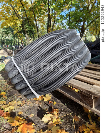 A black plastic pipe lies in a coil at the construction site A black plastic pipe lies in a coil at the construction site 135291948