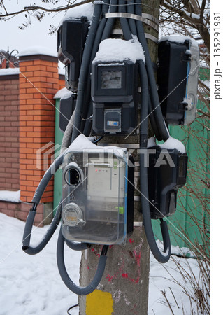 Electric meters for household consumers in private homes hang on a pole 135291981