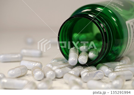 Overdose. Capsules with blue powder scattered on the table. Open green container 135291994