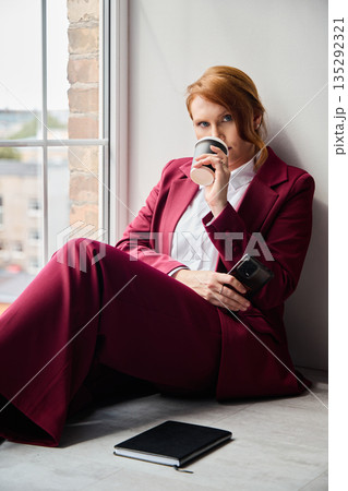 Redheaded executive contemplating with coffee and urban background scenes Redheaded executive contemplating with coffee and urban background scenes 135292321
