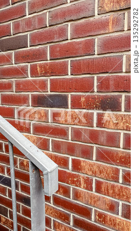 Close-up of a textured red brick wall with a grey metal handrail in the foreground for a loft style Close-up of a textured red brick wall with a grey metal handrail in the foreground for a loft style 135292782