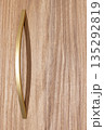 Elegant gold handle rests gently on a textured wooden surface, illuminating minimalist design 135292819