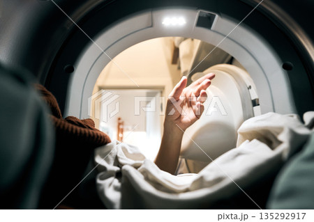 Hand reaching inside washing machine for laundry Hand reaching inside washing machine for laundry 135292917