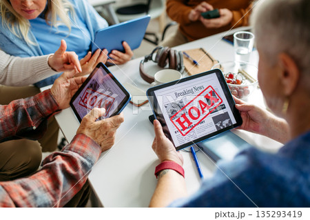 Volunteer teaching seniors how to recognize fake news on digital tablet. Volunteer teaching seniors how to recognize fake news on digital tablet. 135293419