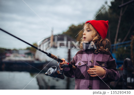 Child enjoying fishing outdoors during cold season. Child enjoying fishing outdoors during cold season. 135293430