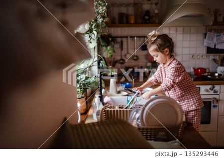 Independent child doing dishes at home. 135293446