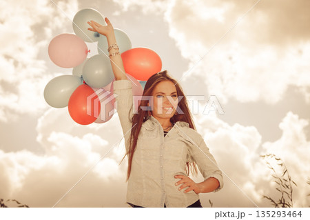 Girl holding balloons sky background 135293464