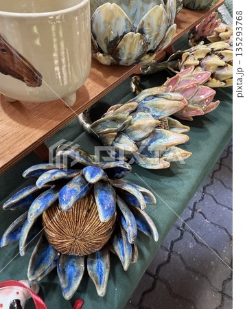 Ceramic artichokes displayed on table at outdoor market with colorful glaze details 135293768