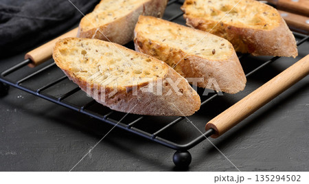 Slices of toasted grain baguette on the grill Slices of toasted grain baguette on the grill 135294502