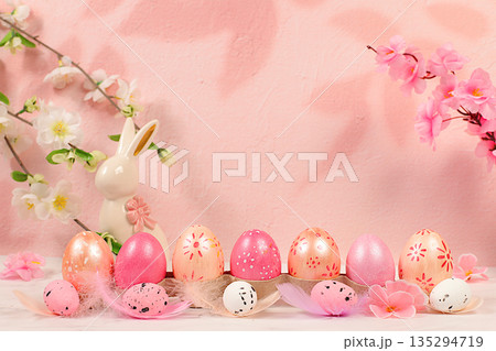 Beautiful Easter banner with decorated festive eggs, sakura and cherry blossom branches, rabbits and feathers. Happy Easter concept. An abstract spring Easter composition with space for text Beautiful Easter banner with decorated festive eggs, sakura and cherry blossom branches, rabbits and feathers. Happy Easter concept. An abstract spring Easter composition with space for text 135294719