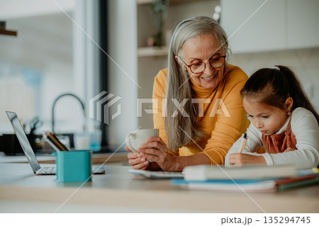 Grandmother helping granddaughter with homework, teaching her math. 135294745