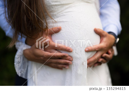 Tender moment of expectant parents holding pregnant belly in anticipation 135294815