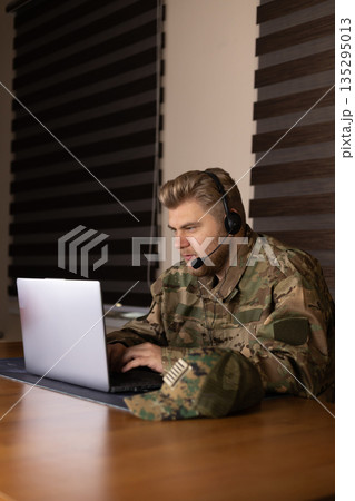 Soldier using laptop and taking notes in office Soldier using laptop and taking notes in office 135295013