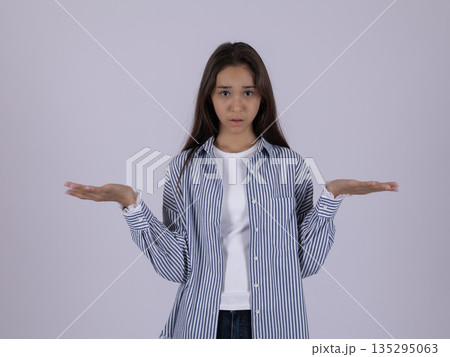 Confident woman in striped shirt shrugging shoulders 135295063