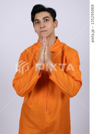 Man in orange uniform praying with hands together 135295069