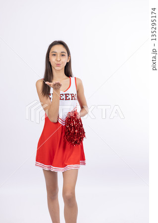 Cheerful cheerleader girl in red uniform with pom-poms Cheerful cheerleader girl in red uniform with pom-poms 135295174