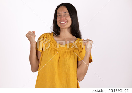 Happy young woman in yellow shirt celebrating success 135295196