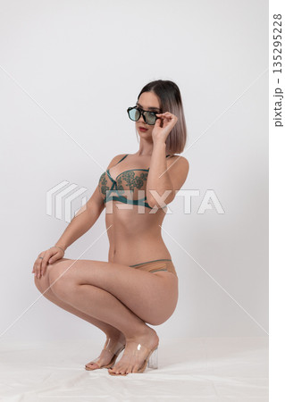 Woman in green lingerie sitting on white floor Woman in green lingerie sitting on white floor 135295228