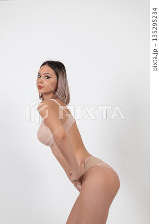 Woman in beige lingerie posing sideways Woman in beige lingerie posing sideways 135295234