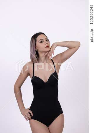 Woman in black bodysuit posing on white background Woman in black bodysuit posing on white background 135295243
