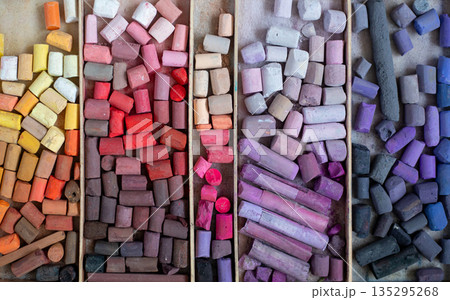 Colored soft pastels crayons in wooden case. Painter's multicolor background. Chalk pieces top view 135295268