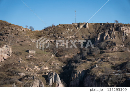 Rocky hills with caves and rugged cliffs in Khndzoresk, Armenia, under a clear blue sky, earthy tones and quiet natural atmosphere Rocky hills with caves and rugged cliffs in Khndzoresk, Armenia, under a clear blue sky, earthy tones and quiet natural atmosphere 135295309