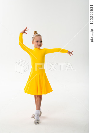 Smiling child in bright yellow practicing choreography with hearing device. Confidence, concentration, and harmony of movement despite deafness, showing inclusion and technological progress in 135295631