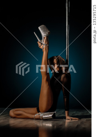 Seated pole dance pose with raised leg and glitter heels, elongated line and elegant hand placement framing editorial glamour vibe, soft rim lighting highlighting skin tone and poised expression Seated pole dance pose with raised leg and glitter heels, elongated line and elegant hand placement framing editorial glamour vibe, soft rim lighting highlighting skin tone and poised expression 135295715