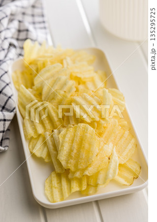 Wavy potato chips on plate on white table. 135295725