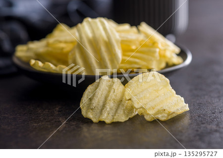 Wavy potato chips on black table. 135295727