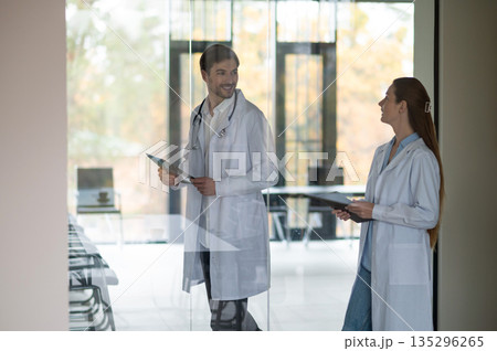 Female doctor standing near the flipchart and presenting something to a new doctor 135296265