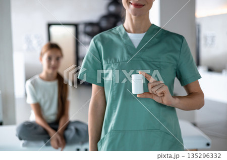 Healthcare professional showing medication container during pediatric visit 135296332