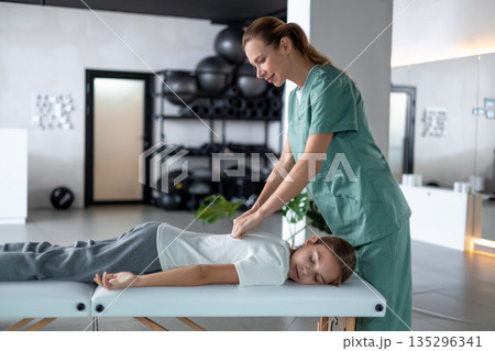 Woman therapist doing little girl calf muscle massaging Woman therapist doing little girl calf muscle massaging 135296341