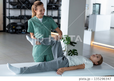 Woman therapist massaging little girl leg for recovery 135296347