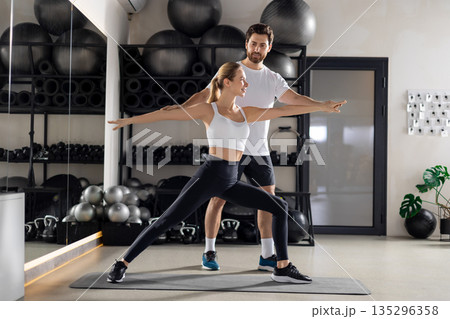 Blonde woman working with a coach in the gym and looking concentrated Blonde woman working with a coach in the gym and looking concentrated 135296358