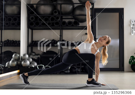 Blonde young woman exercising in the gym and looking determined Blonde young woman exercising in the gym and looking determined 135296366